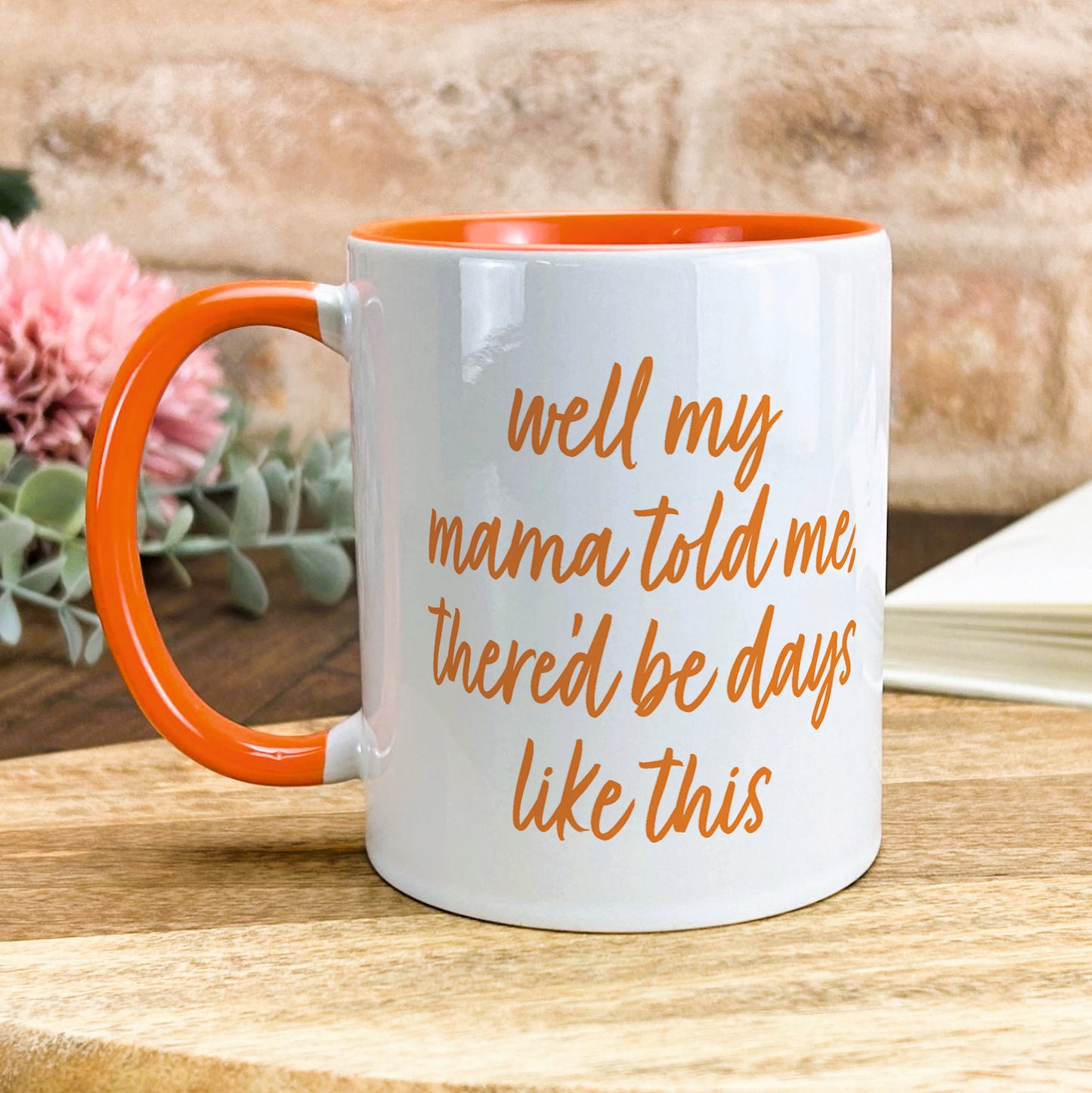 a white and orange coffee mug sitting on top of a wooden table