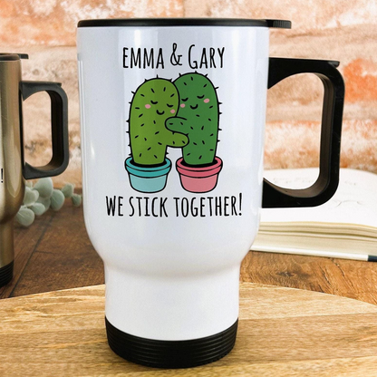 A white travel mug with a black handle, featuring a cartoon image of two cacti hugging and the text "Emma & Gary We stick together!"