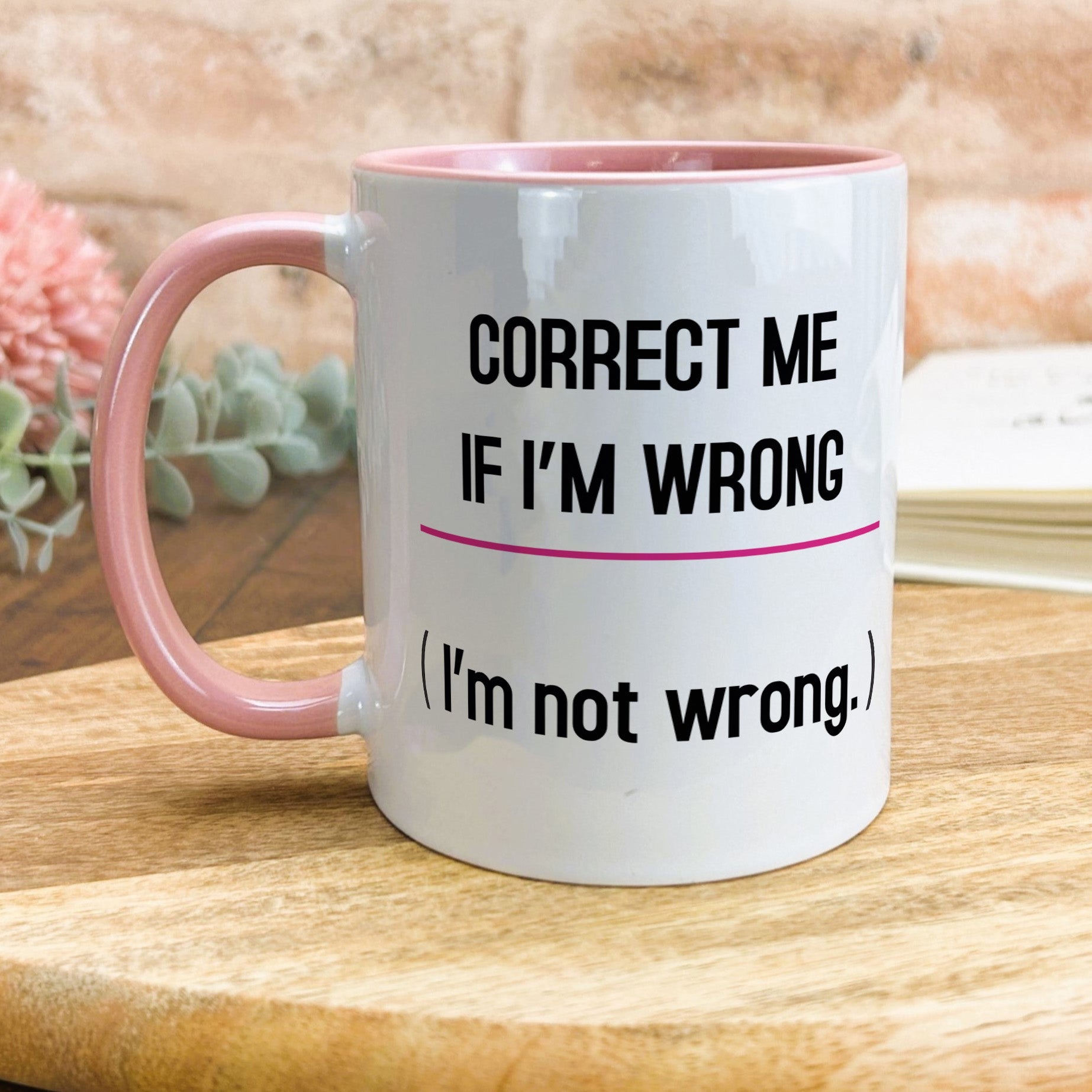 a pink and white coffee mug sitting on top of a wooden table