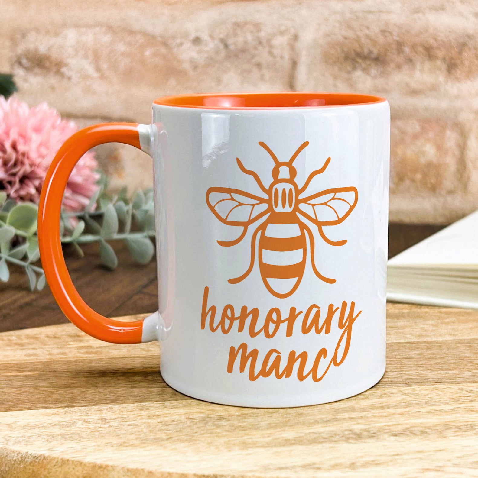 a white and orange coffee mug with a bee on it