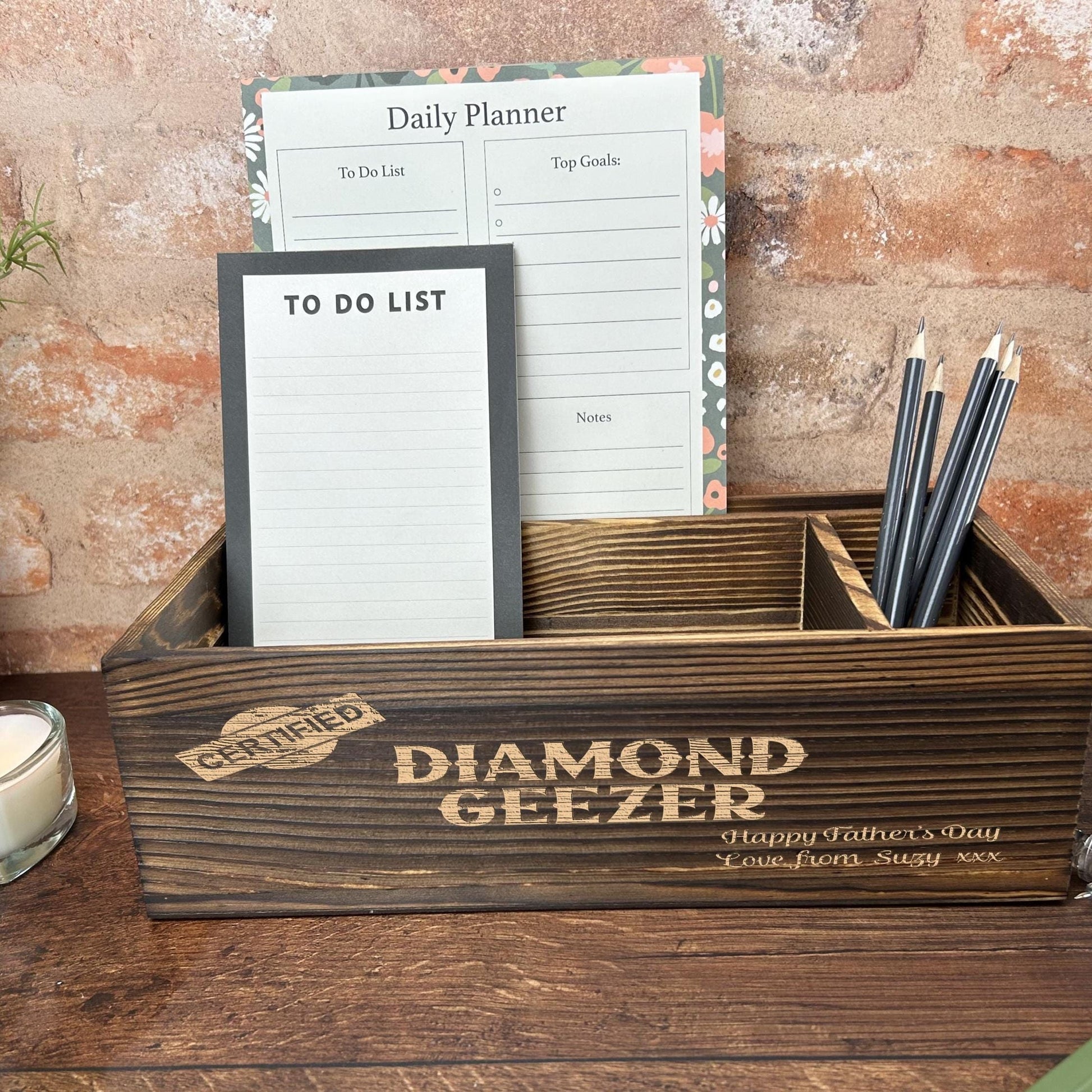a wooden desk with a notepad, pen holder and a candle