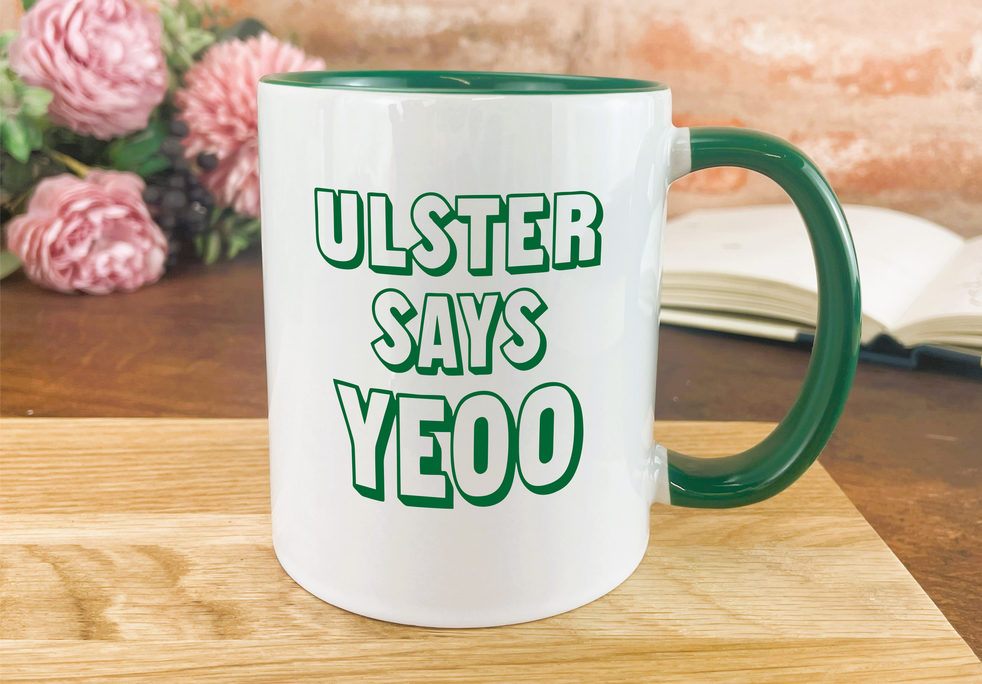 a green and white coffee mug sitting on top of a wooden table