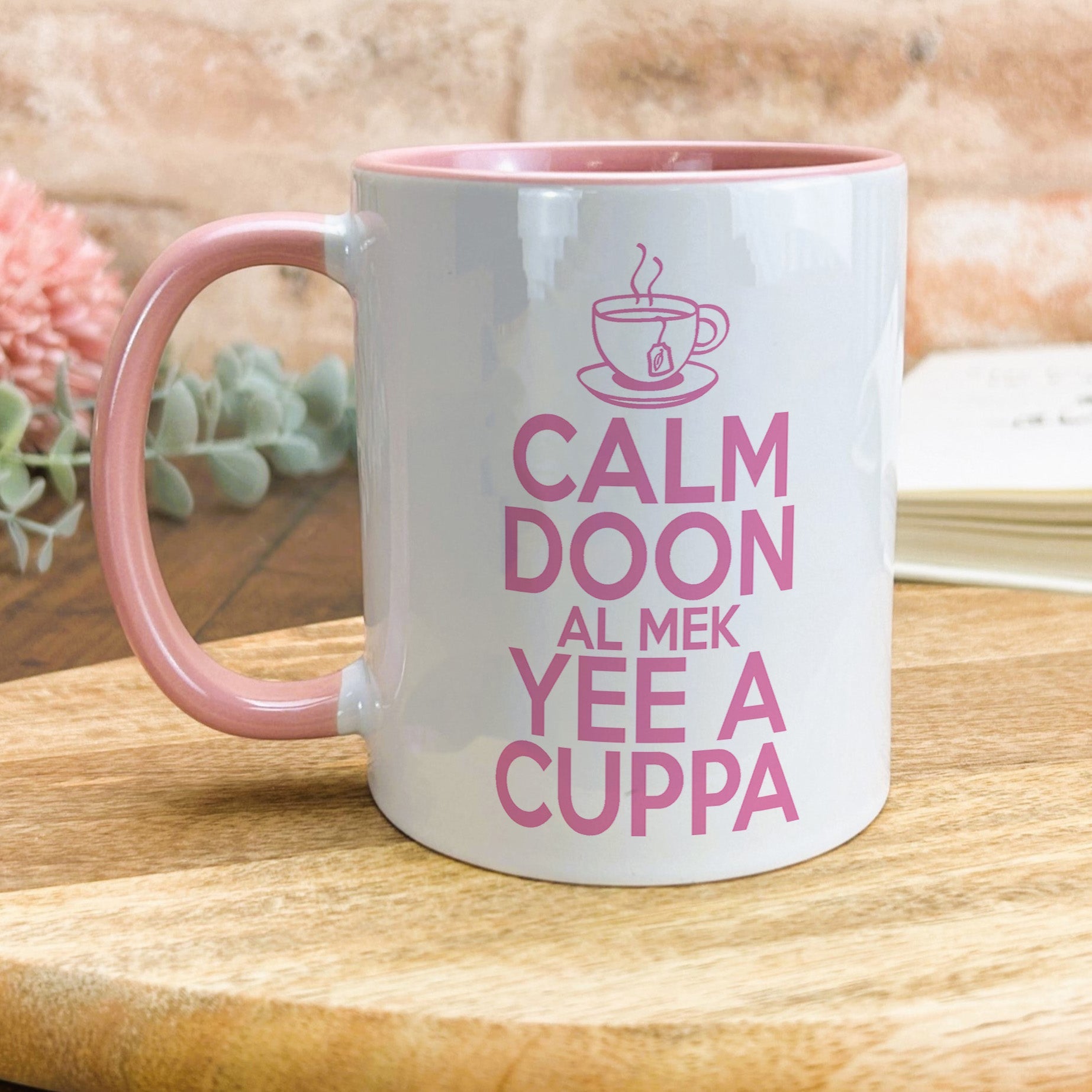 a pink and white coffee mug sitting on top of a wooden table