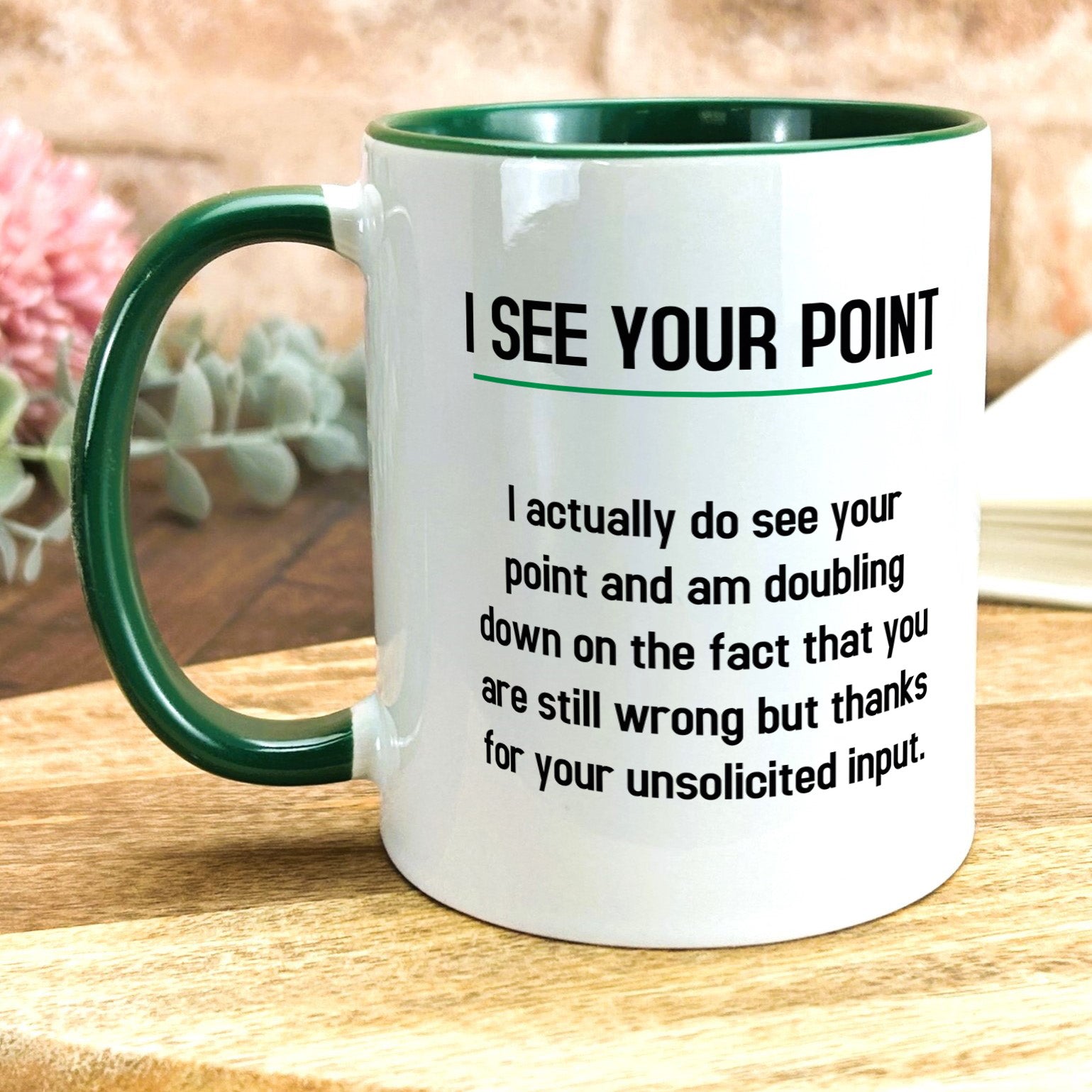 a green and white coffee mug sitting on top of a wooden table