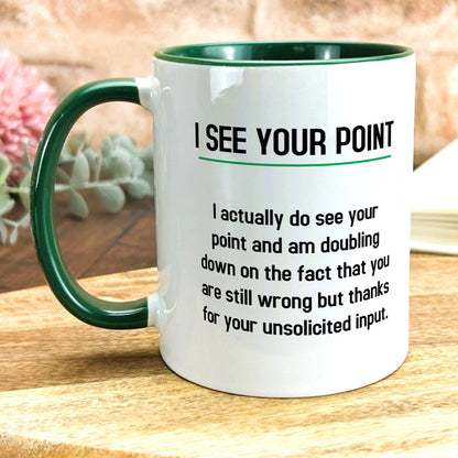 a green and white coffee mug sitting on top of a wooden table