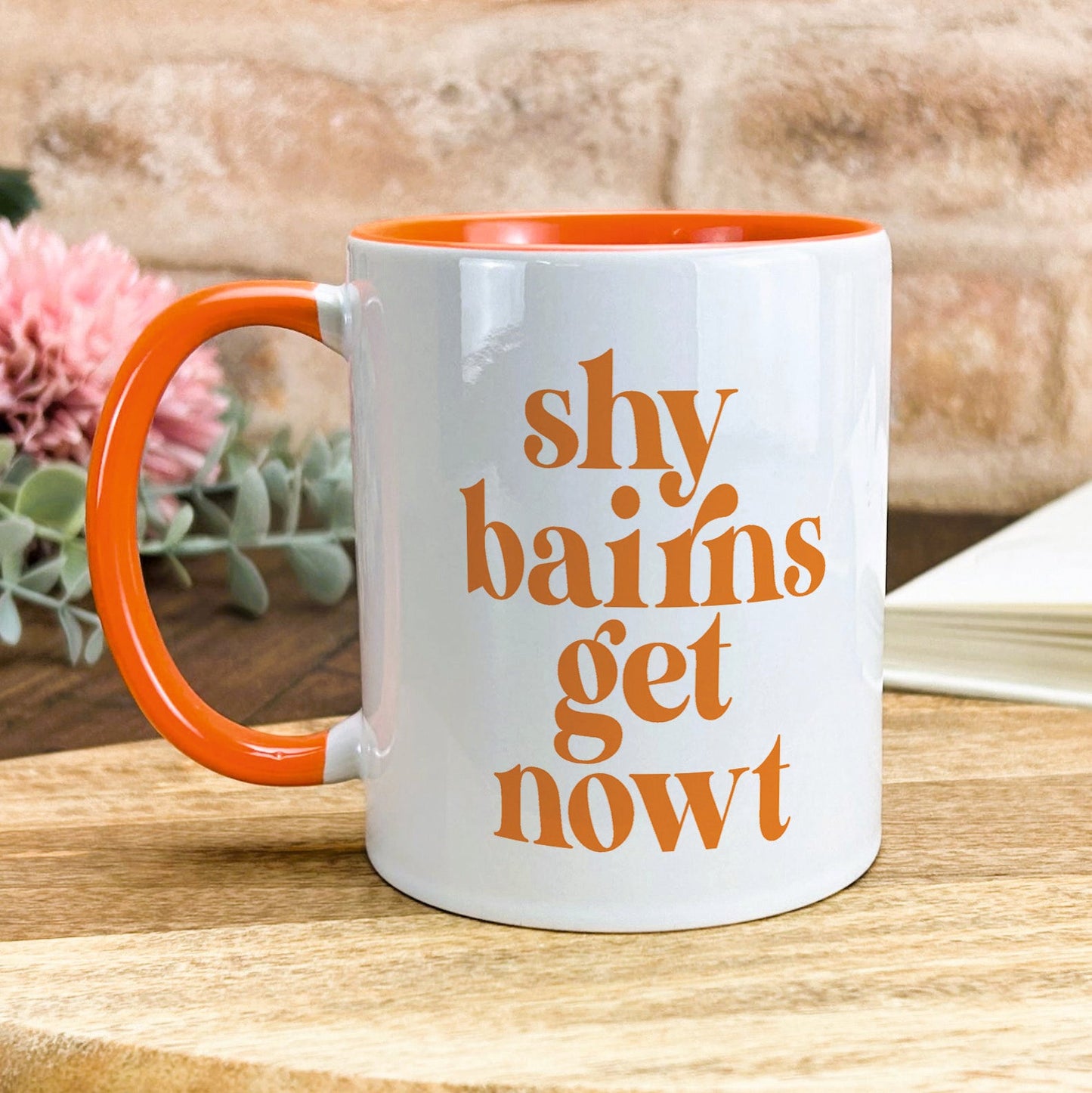 a white and orange coffee mug sitting on top of a wooden table
