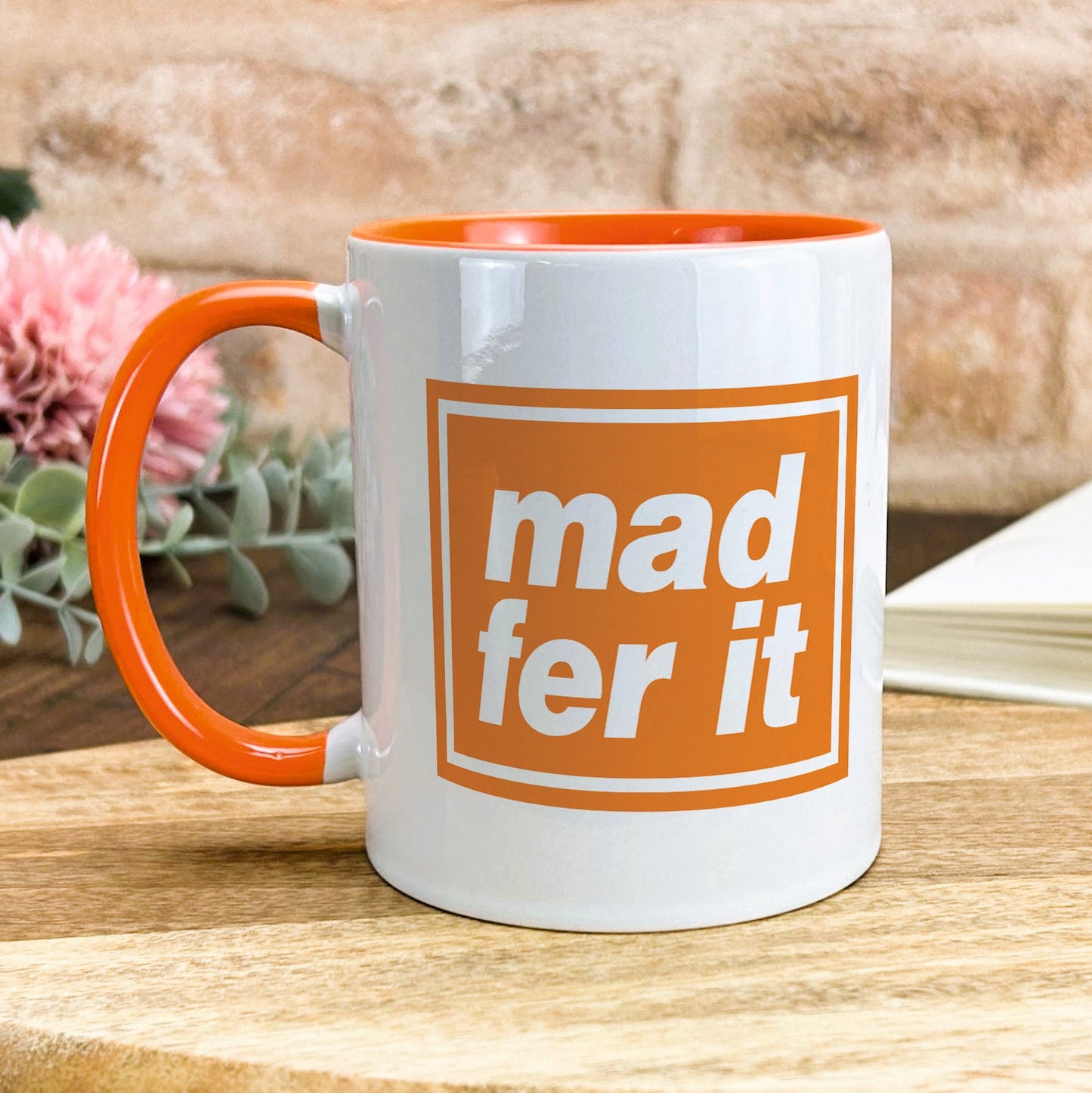 a white and orange mug sitting on top of a wooden table