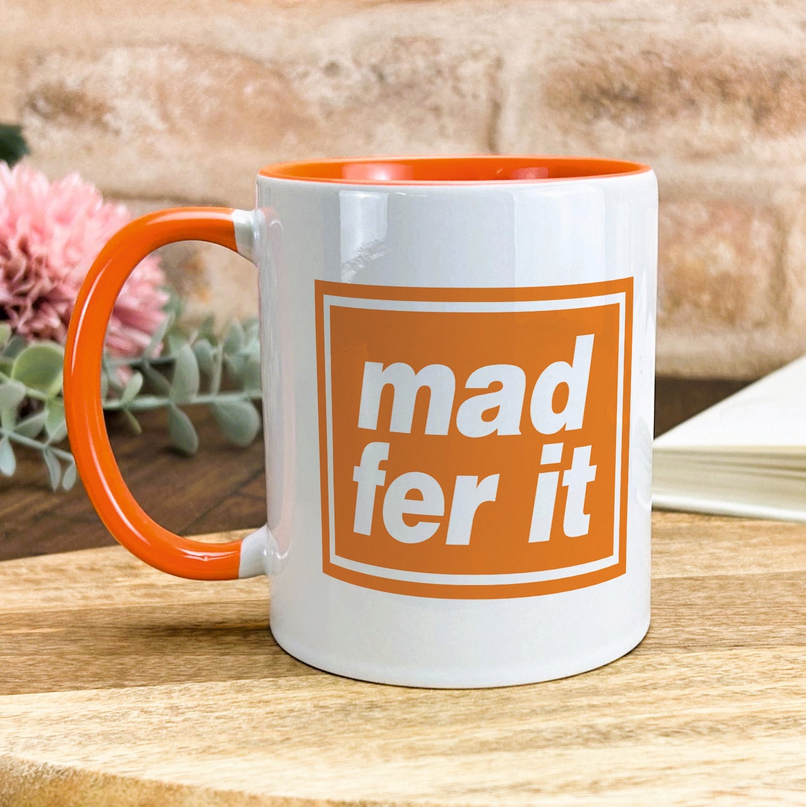 a white and orange mug sitting on top of a wooden table