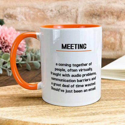 a white and orange coffee mug sitting on top of a wooden table