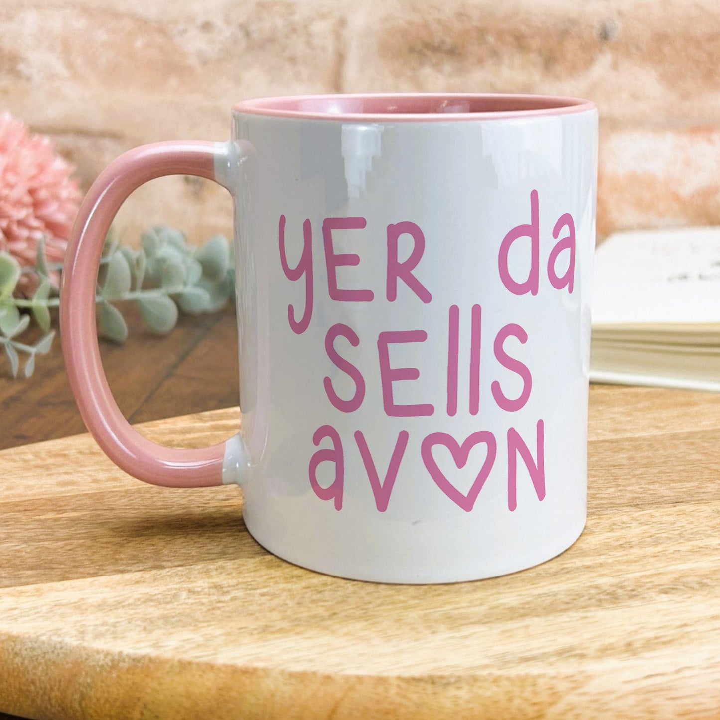 a pink and white coffee mug sitting on top of a wooden table