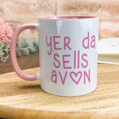 a pink and white coffee mug sitting on top of a wooden table