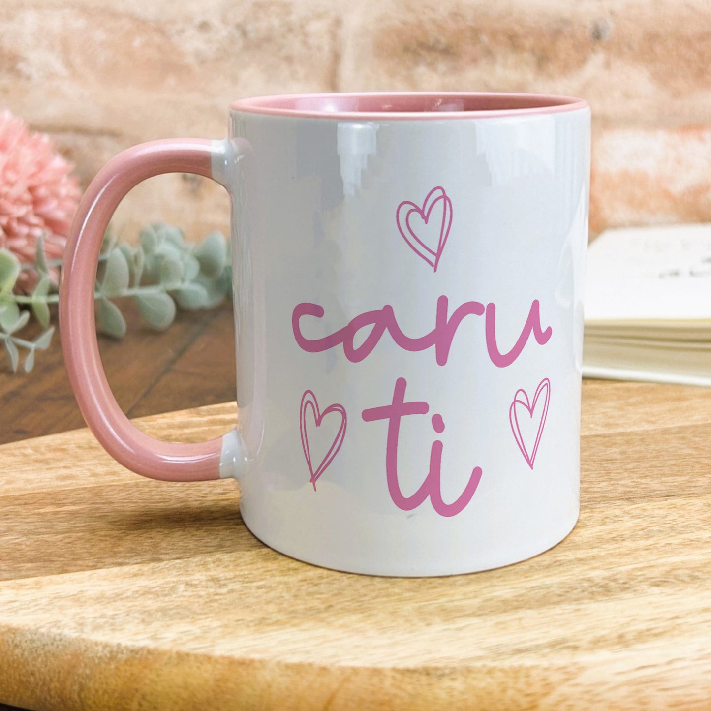 a pink and white coffee mug sitting on top of a wooden table