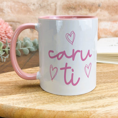 a pink and white coffee mug sitting on top of a wooden table