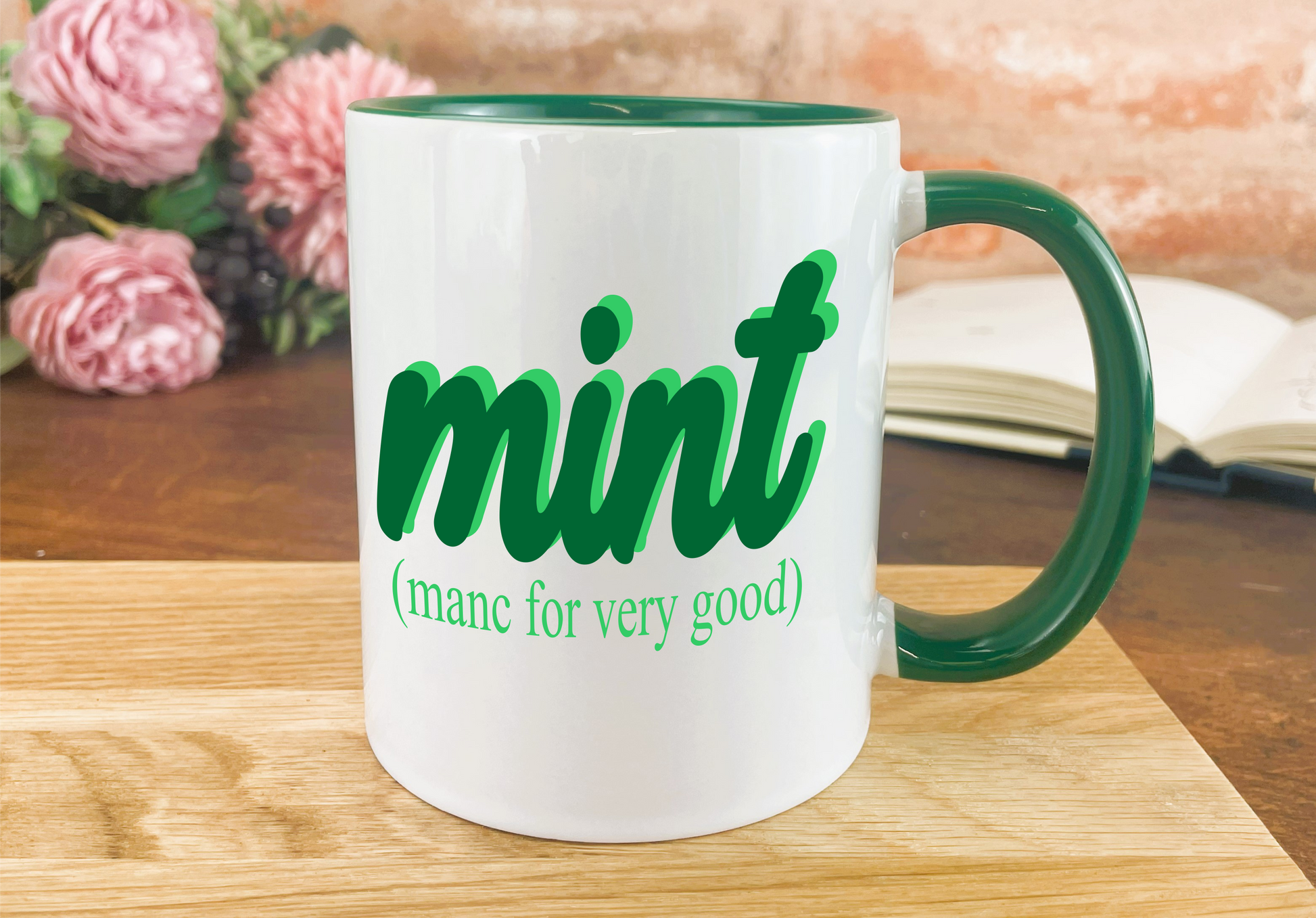 a green and white coffee mug sitting on top of a wooden table
