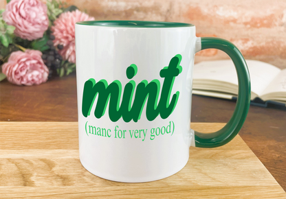 a green and white coffee mug sitting on top of a wooden table