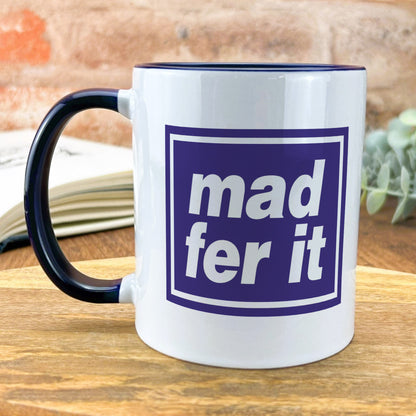 a white and blue mug sitting on top of a wooden table