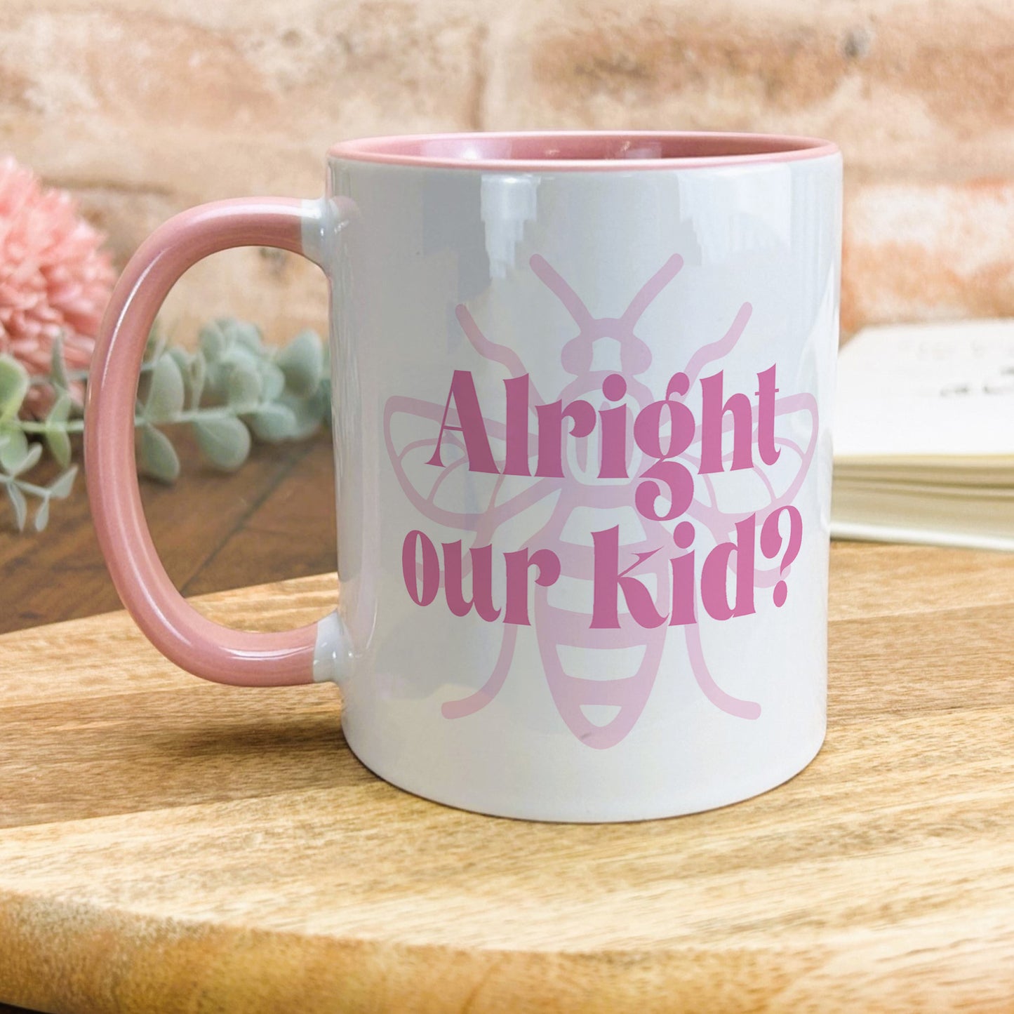 a pink and white coffee mug sitting on top of a wooden table