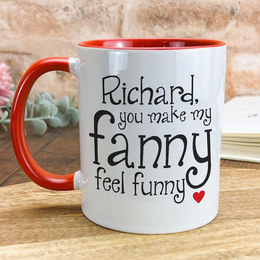 A white mug with a red handle, featuring a humorous text that reads "Richard, you make my fanny feel funny" along with a small red heart symbol.