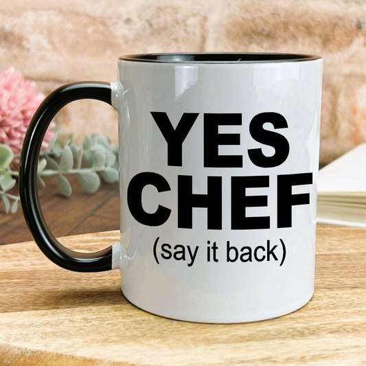 A white mug with black text and a black handle, placed on a wooden surface.