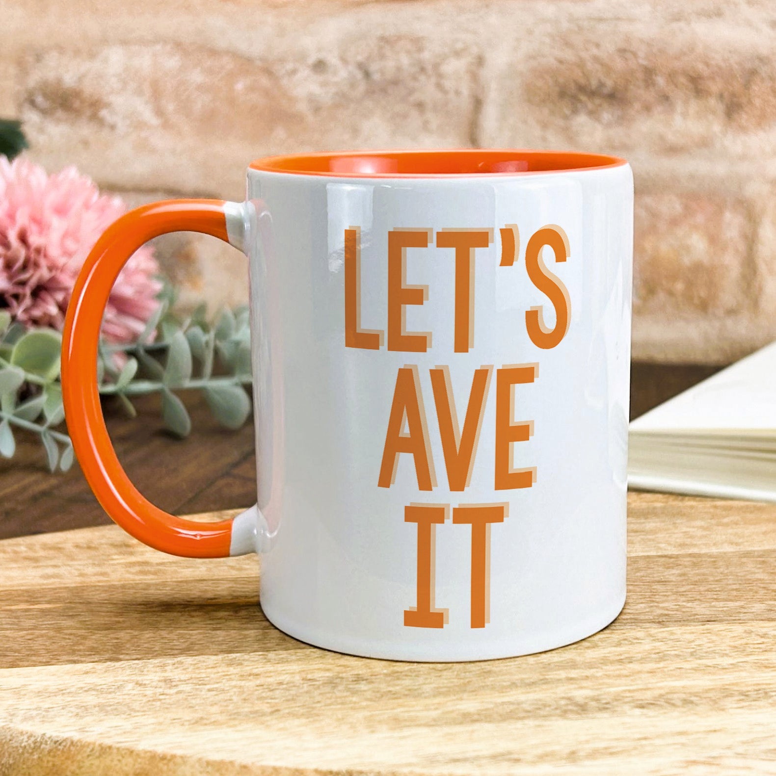 a white and orange coffee mug sitting on top of a wooden table
