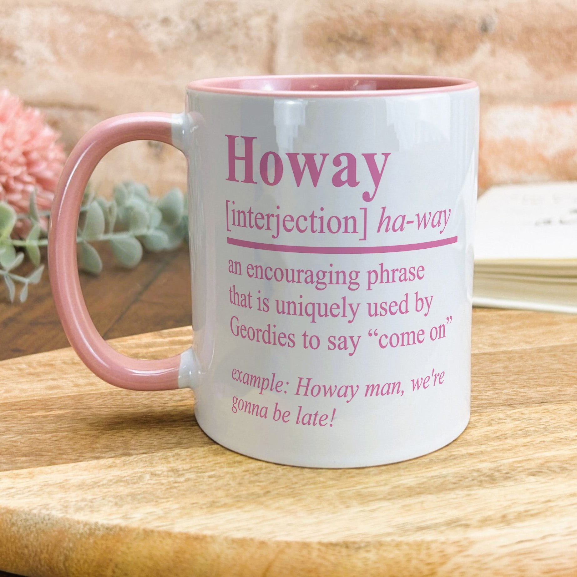 a pink and white coffee mug sitting on top of a wooden table