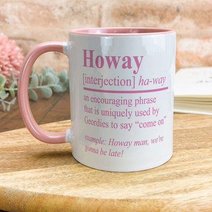 a pink and white coffee mug sitting on top of a wooden table