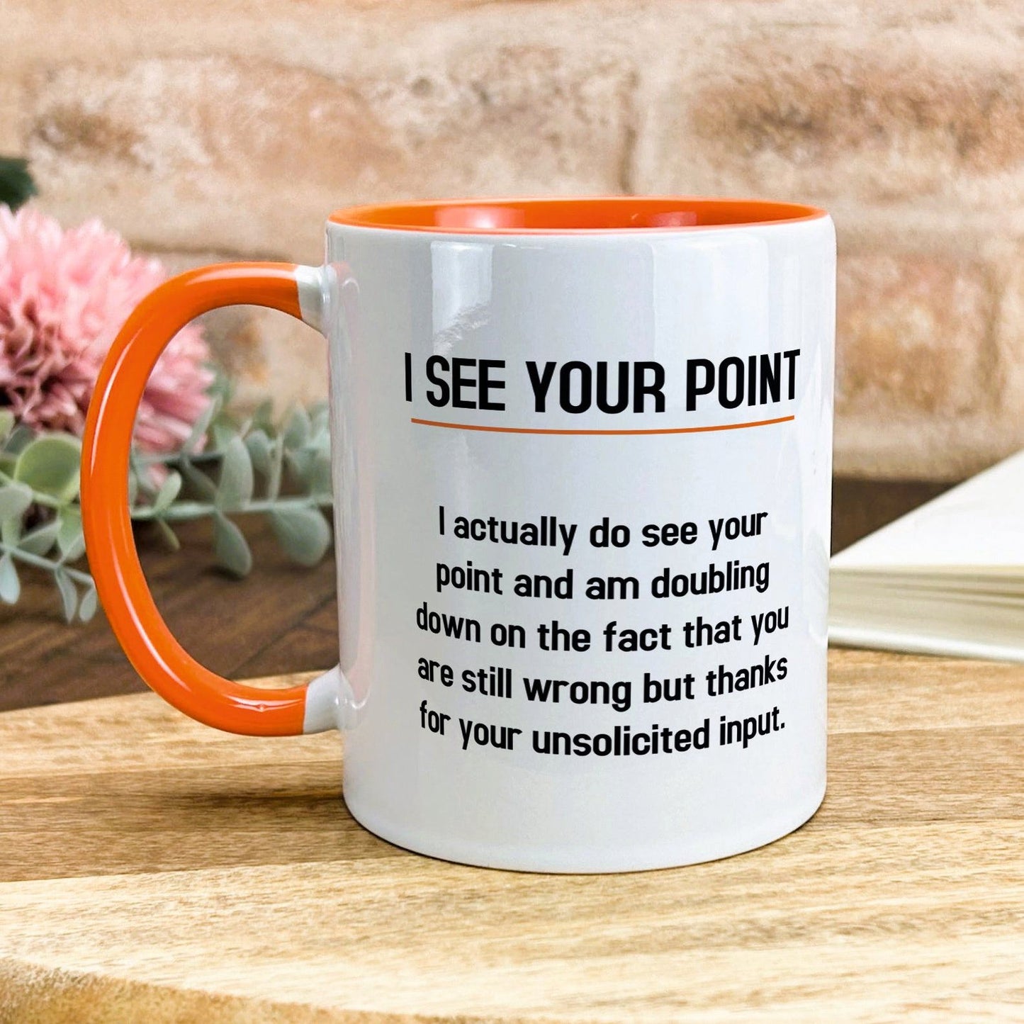 a white and orange coffee mug sitting on top of a wooden table