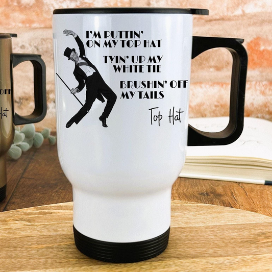 A white travel mug with a black handle and a black and white illustration of a man dancing. The mug has text on it that says "I'm puttingin' on my top hat, twin' up my white tie, brushin' off my my tails, Top Hat".