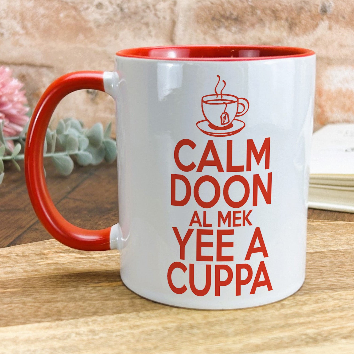 a red and white coffee mug sitting on top of a wooden table