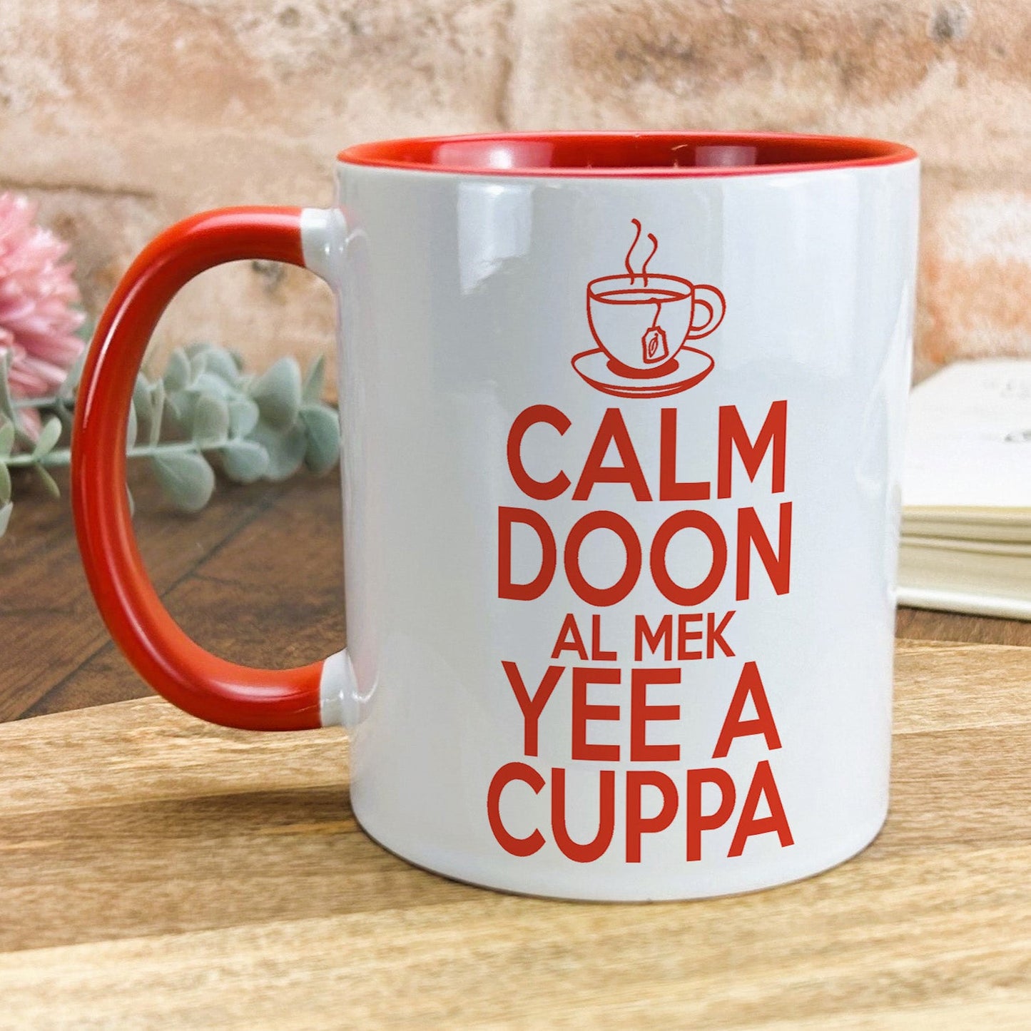 a red and white coffee mug sitting on top of a wooden table