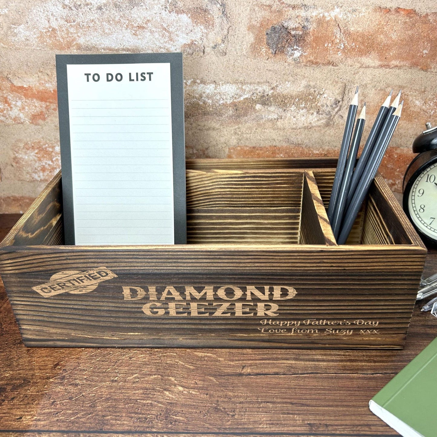 a desk with a clock, notepad and pen holder