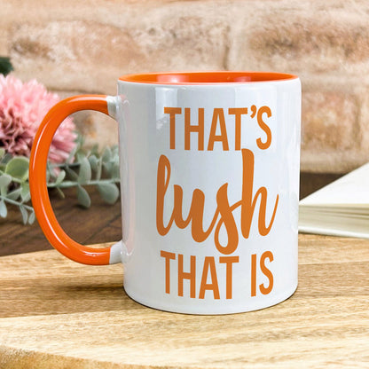 a white and orange coffee mug sitting on top of a wooden table