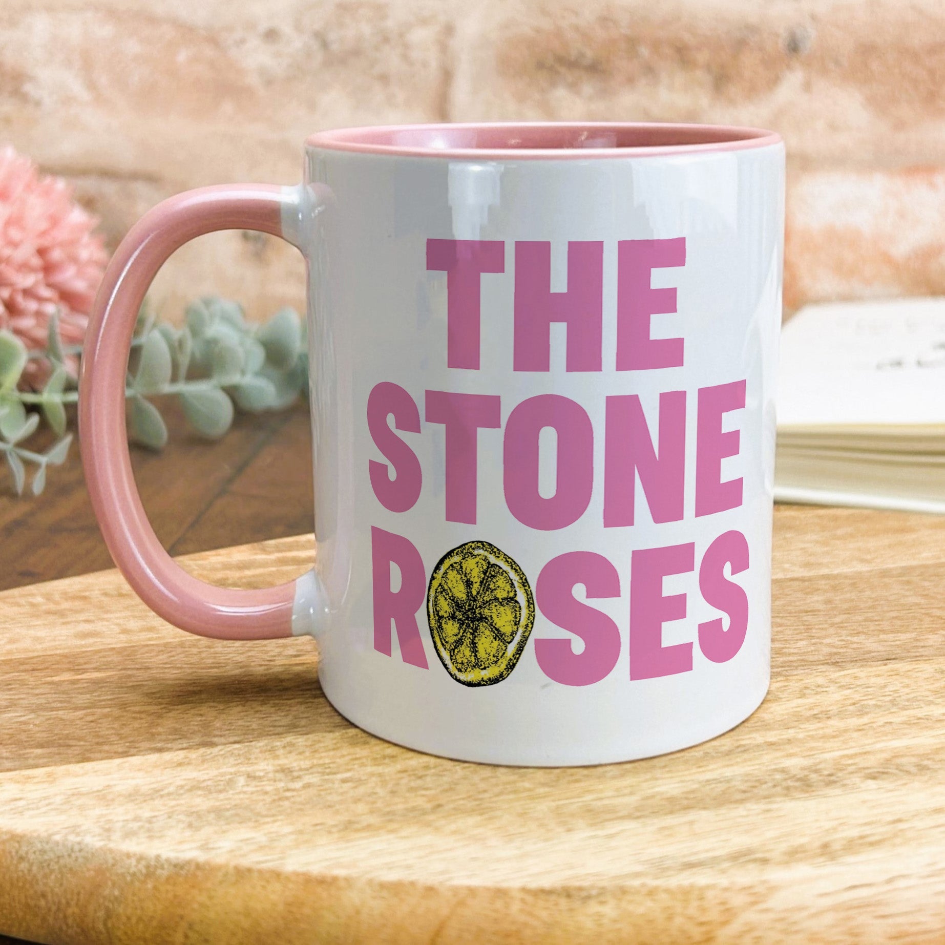a pink and white coffee mug sitting on top of a wooden table