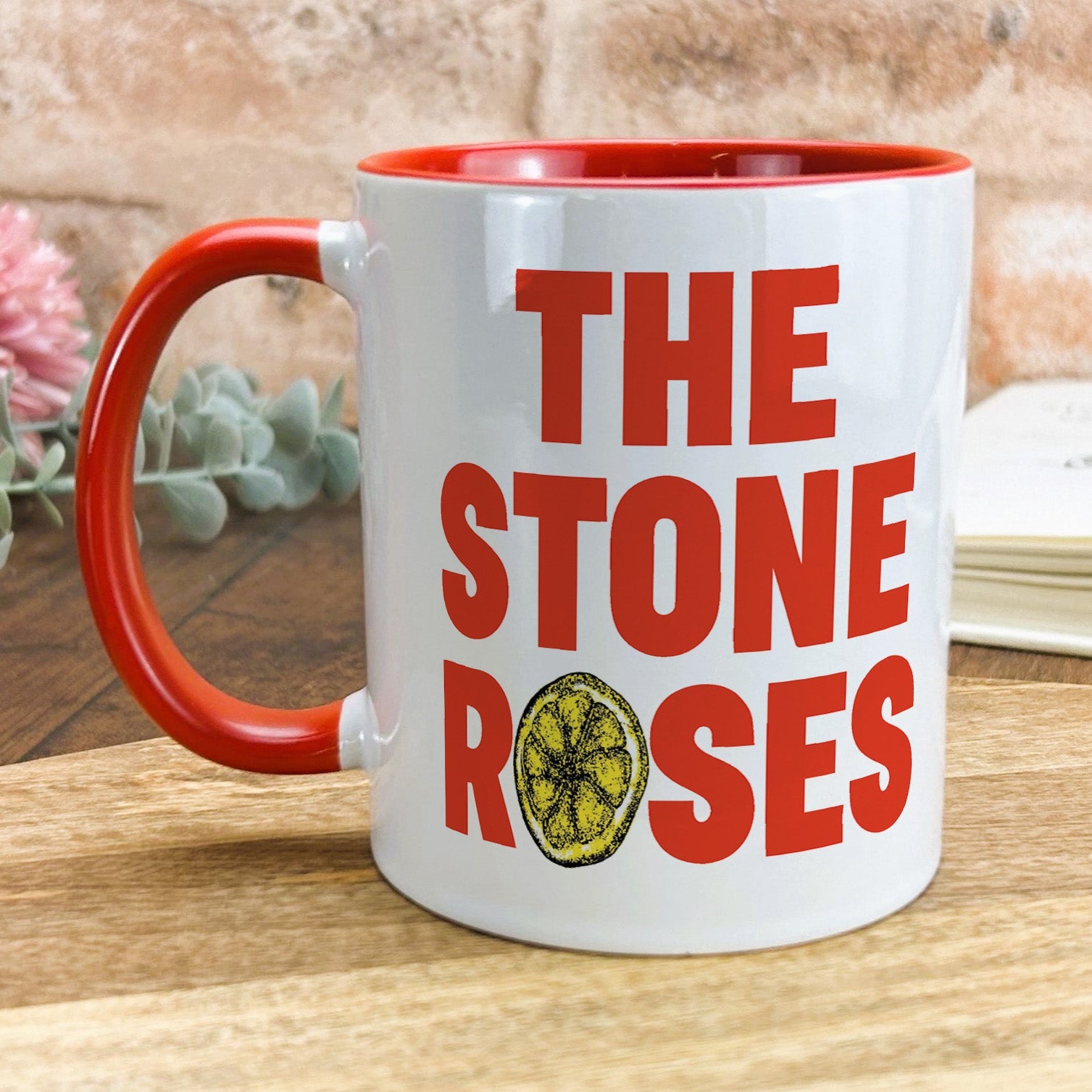 a red and white coffee mug with the words the stone roses on it