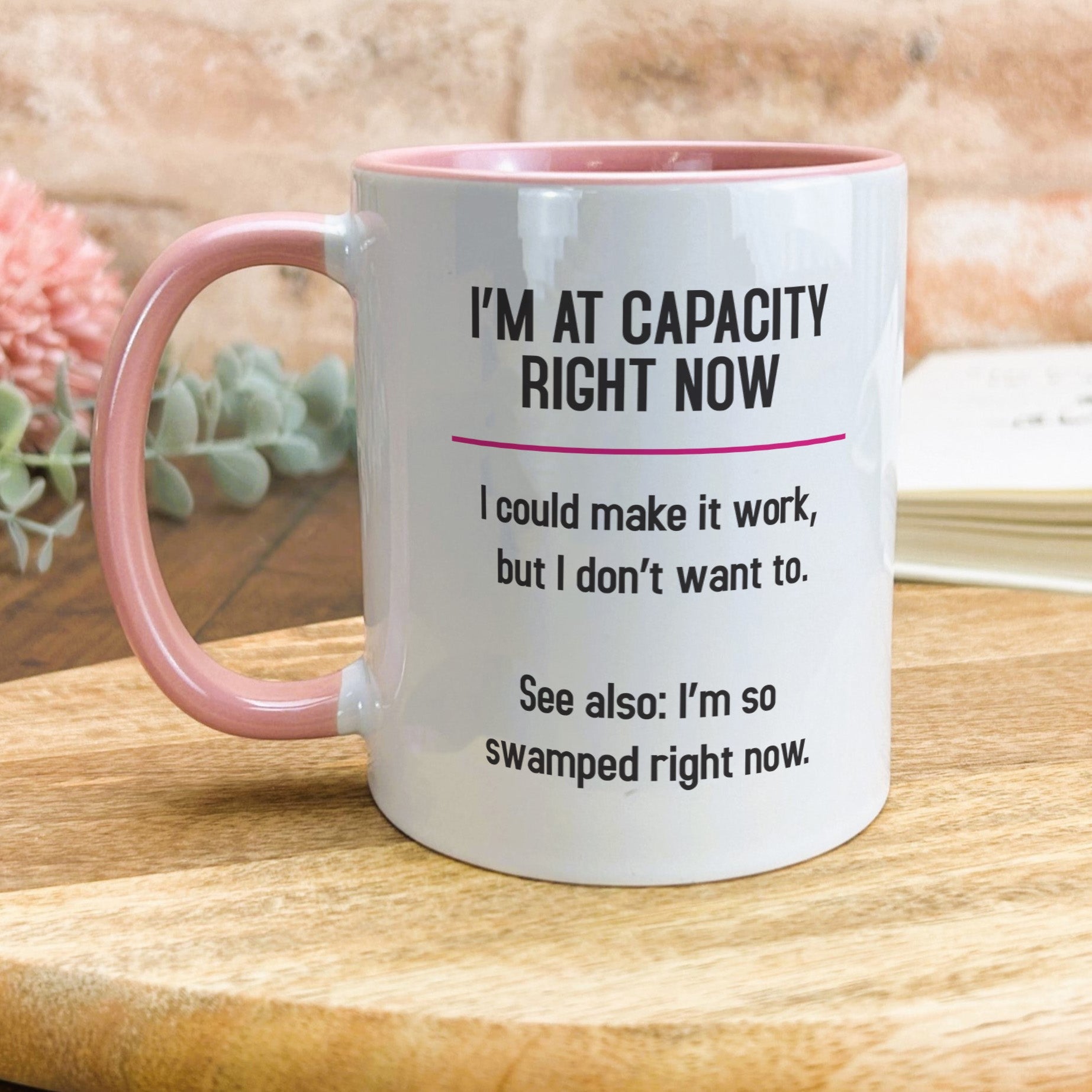 a pink and white coffee mug sitting on top of a wooden table