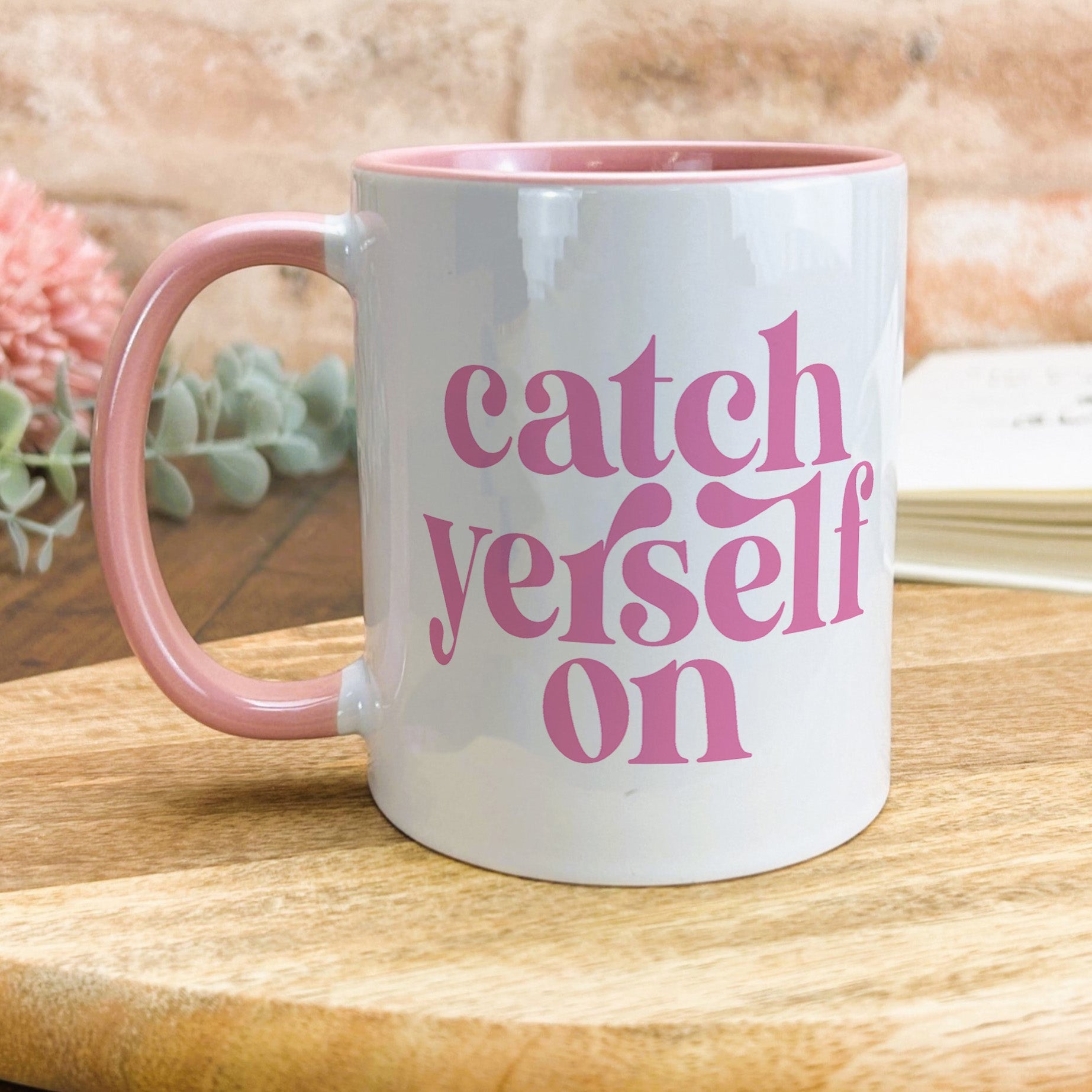 a pink and white coffee mug sitting on top of a wooden table