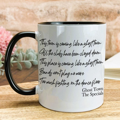 A white coffee mug with black text printed on it, placed on a wooden surface.