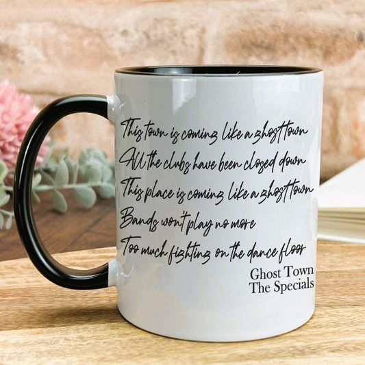 A white coffee mug with black text printed on it, placed on a wooden surface.