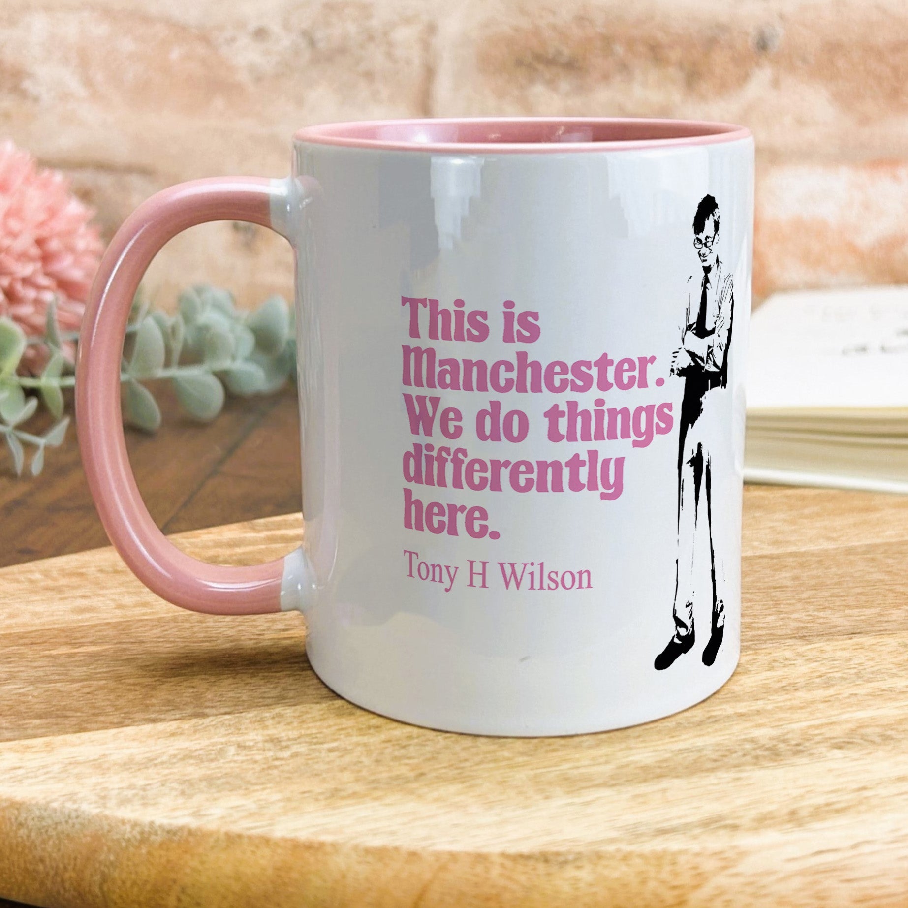 a pink and white coffee mug sitting on top of a wooden table