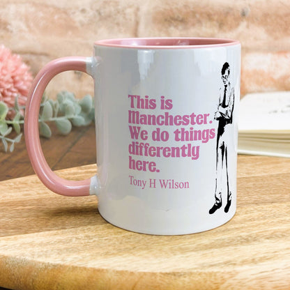 a pink and white coffee mug sitting on top of a wooden table