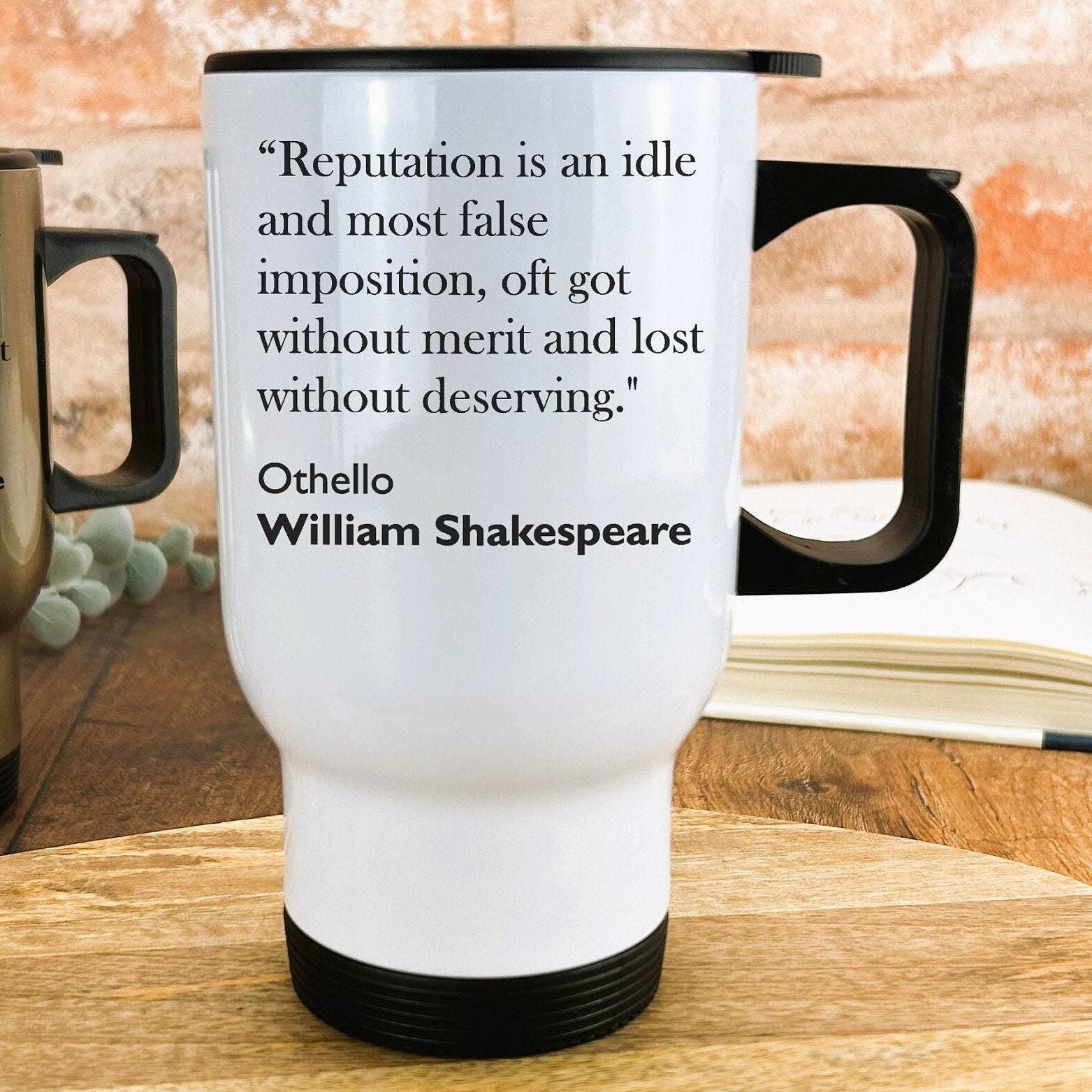 A white travel mug with a quote by William Shakespeare printed on it, placed on a wooden surface.