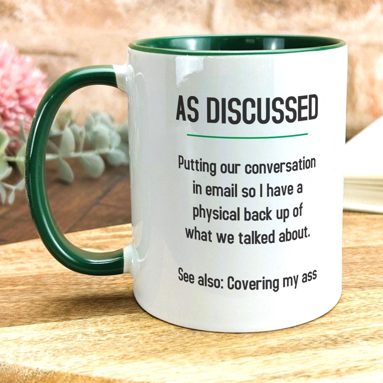 a green and white coffee mug sitting on top of a wooden table