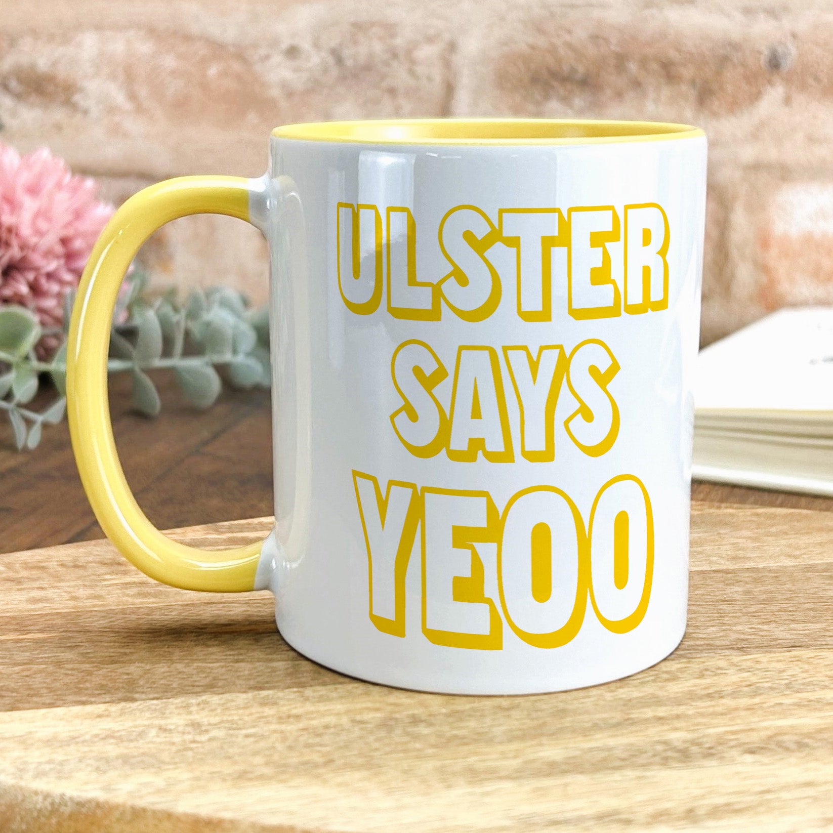 a yellow and white coffee mug sitting on top of a wooden table
