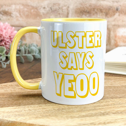 a yellow and white coffee mug sitting on top of a wooden table