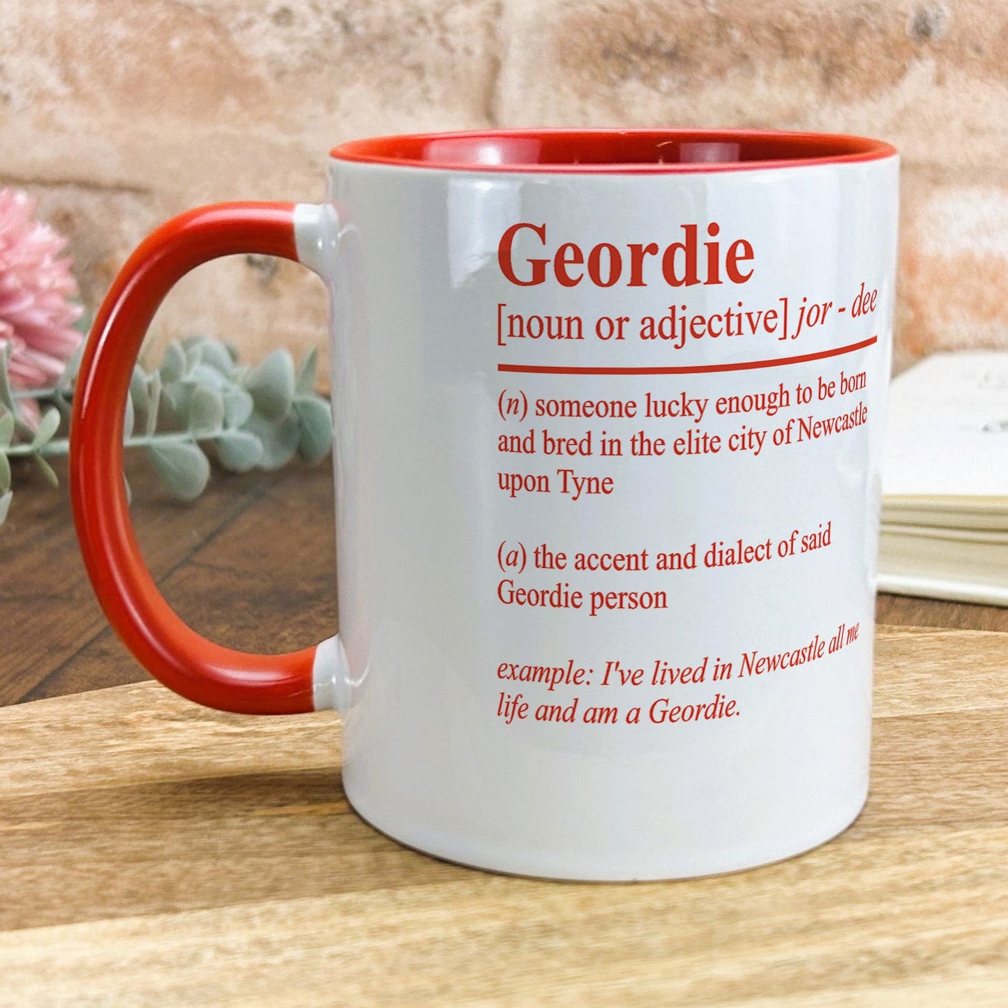 a red and white mug sitting on top of a wooden table
