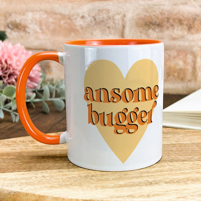 a white and orange coffee mug with an orange handle