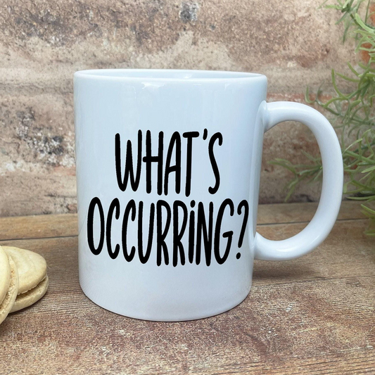 A white ceramic mug with the text "WHAT'S OCCURRING?" printed on it.