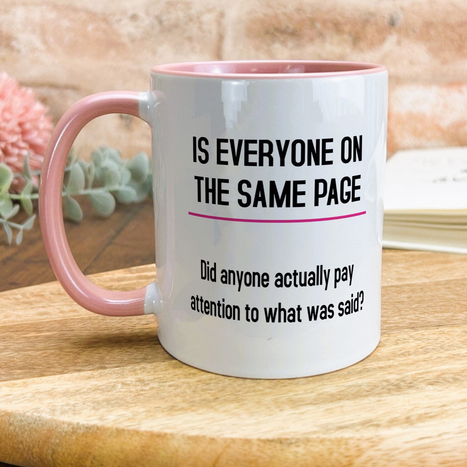 a pink and white coffee mug sitting on top of a wooden table