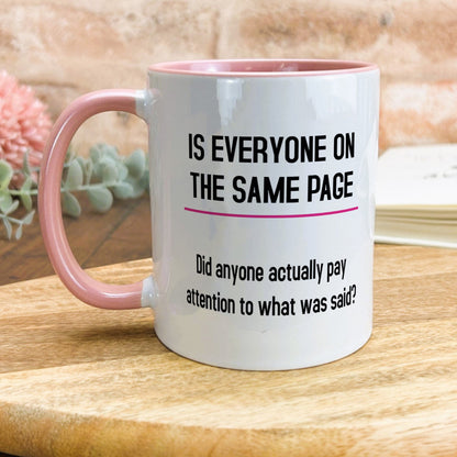 a pink and white coffee mug sitting on top of a wooden table