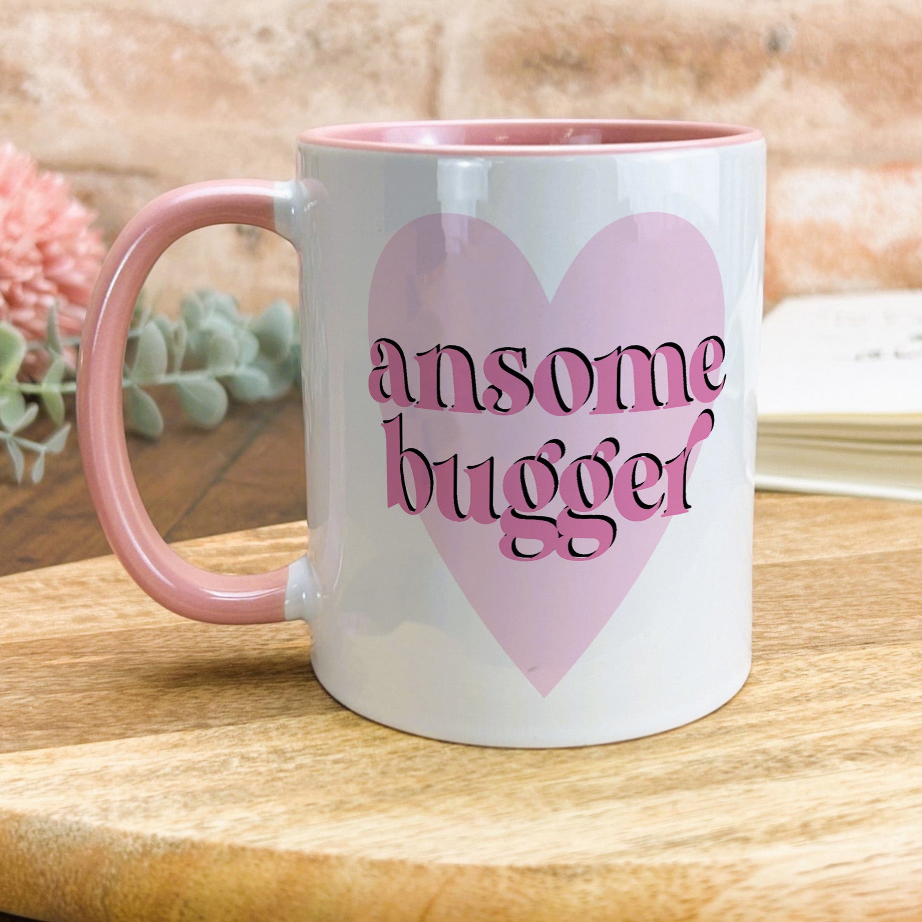 a pink and white coffee mug sitting on top of a wooden table